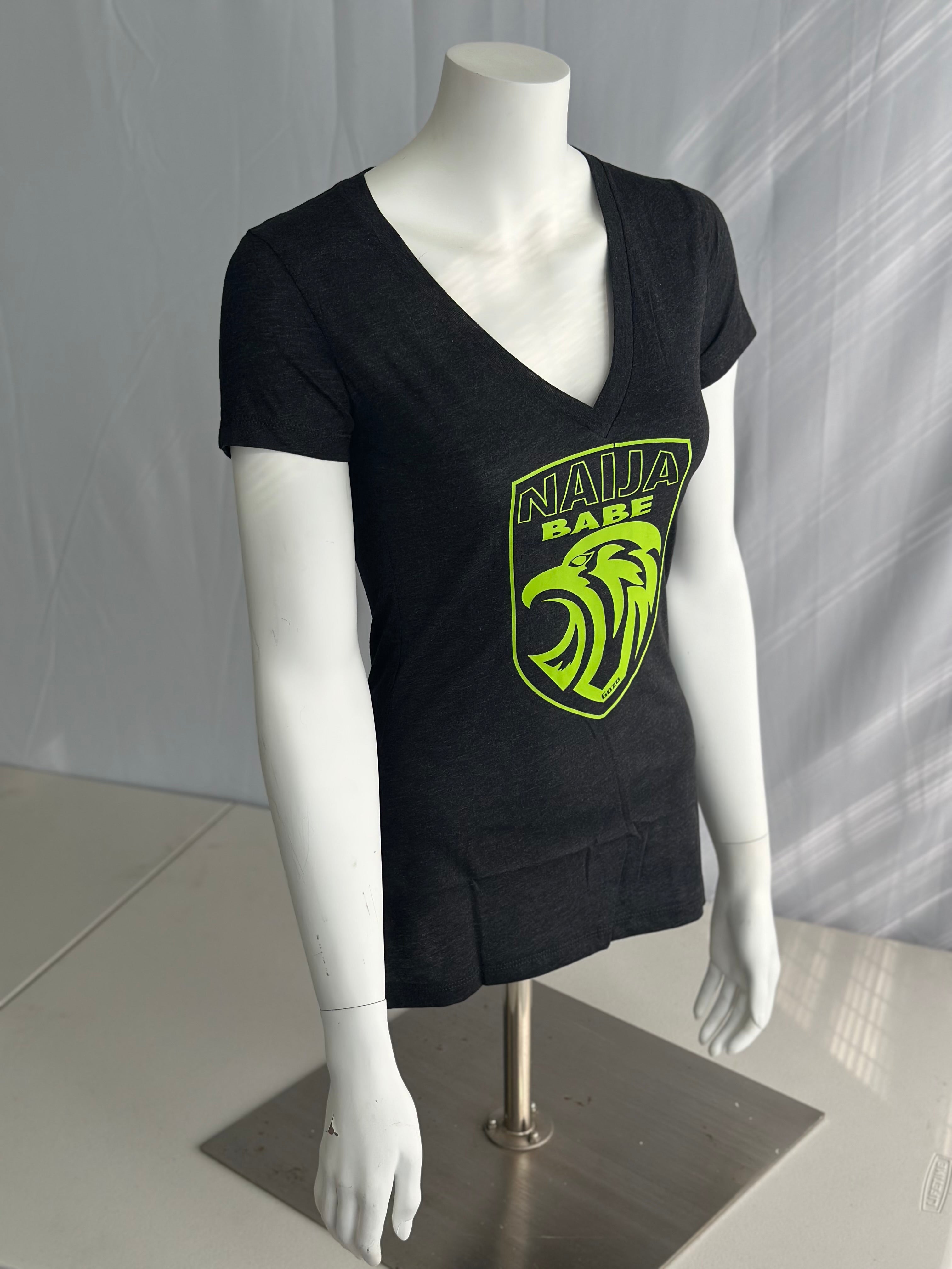 An ash- gray short-sleeve V-neck t-shirt displayed on a white mannequin torso. The shirt features a large neon green and yellow graphic on the front with the text 'NAIJA BABE' and a stylized eagle head
